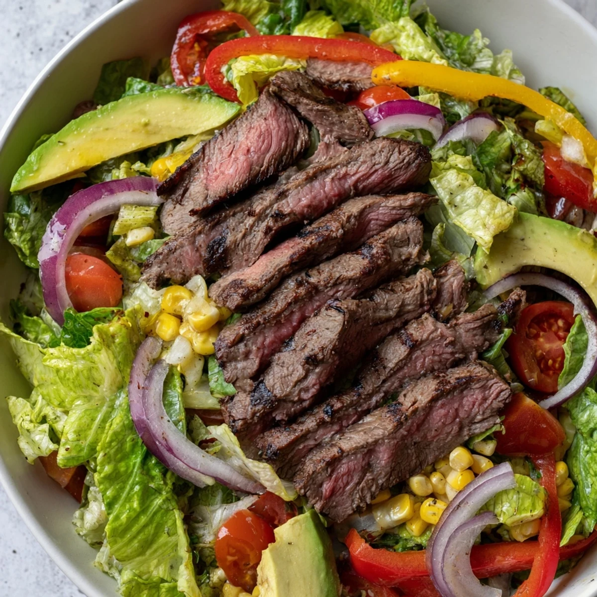 Close-up of a hearty serving showing tender beef, crunchy vegetables, and a zesty lime vinaigrette drizzle.
