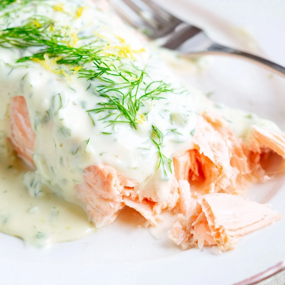 Perfectly baked Baked Salmon with Lemon Dill Sauce served alongside bright green asparagus on a white plate.
