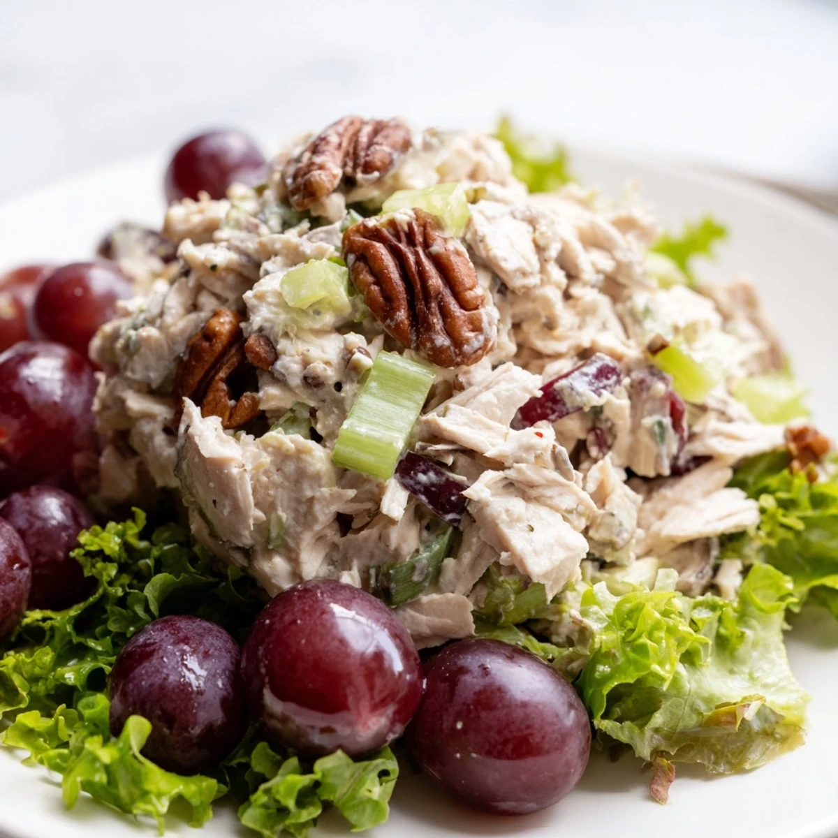 Freshly tossed Chicken Salad with Pecans and red grapes in a rustic bowl with crackers.