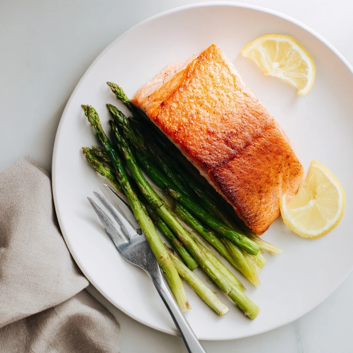 Perfectly crisp salmon fillets and tender asparagus spears are plated with lemon wedges for a fresh, vibrant weeknight meal.