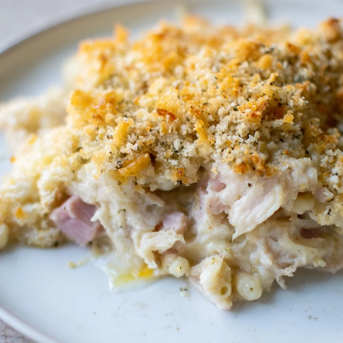 Freshly baked Chicken Cordon Bleu Casserole served with green beans on a rustic wooden table.