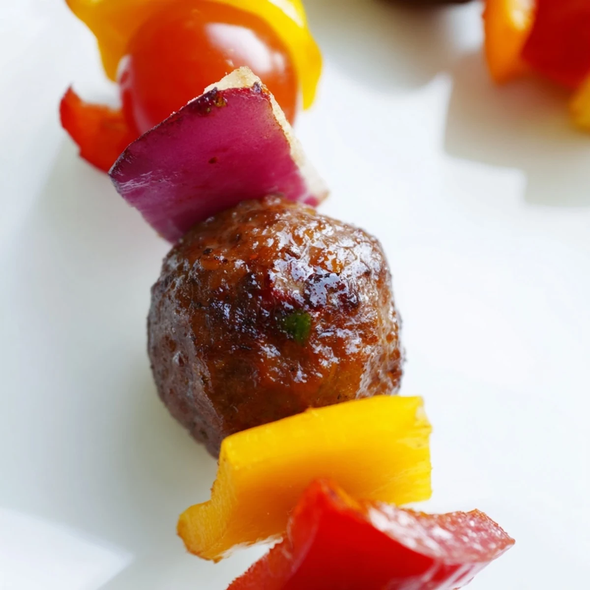 Juicy, seasoned beef meatballs threaded onto skewers with crisp bell peppers and cherry tomatoes, served with lemon wedges for a vibrant party appetizer.