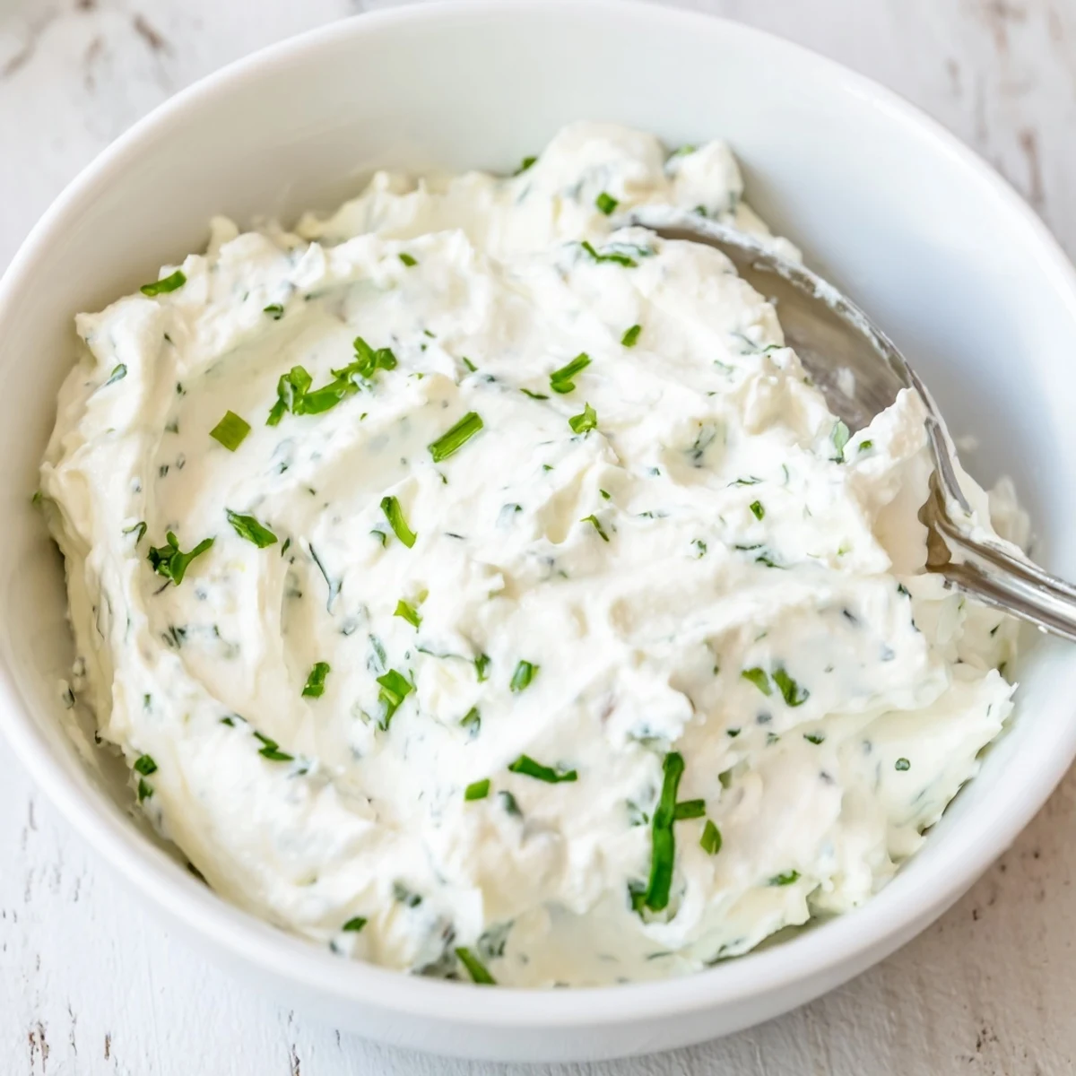 A bowl of Creamy Appetizer Spread Dip garnished with fresh chives and parsley, ready for party dipping.