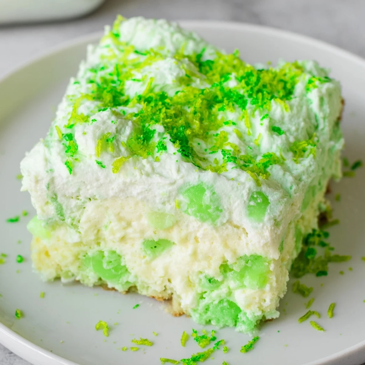 Festive St. Patricks Day Lime Poke Cake with creamy topping and vibrant green gelatin soaking into the fluffy white cake base.