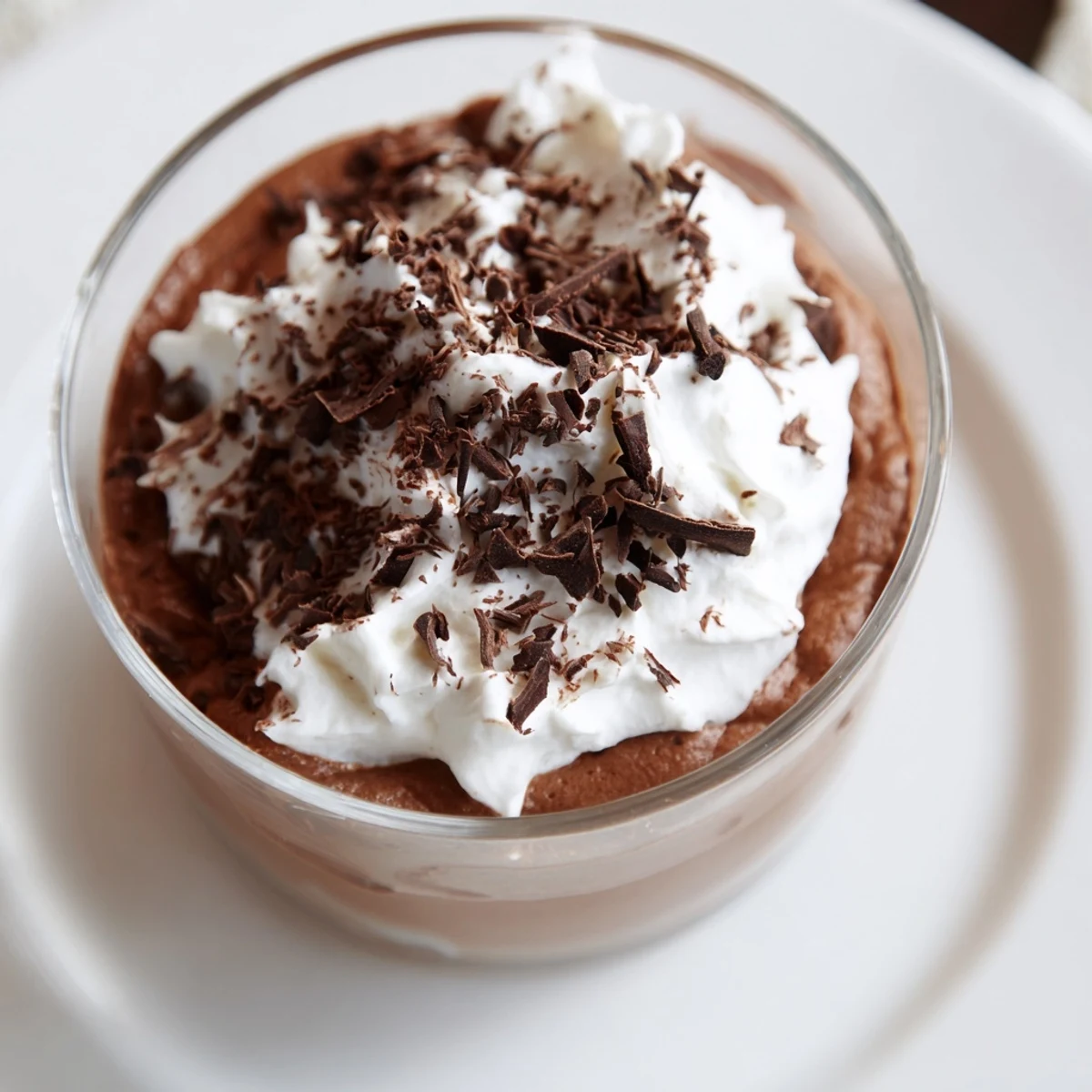 Silky Chocolate Mousse with Whipped Cream served in elegant glasses with chocolate shavings.
