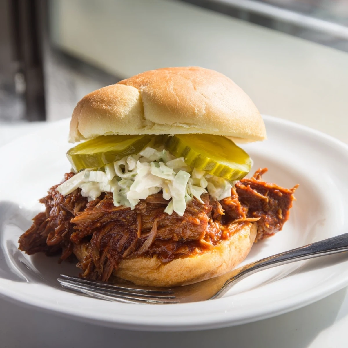 Beef Brisket Sliders piled high with tangy BBQ sauce and pickles.