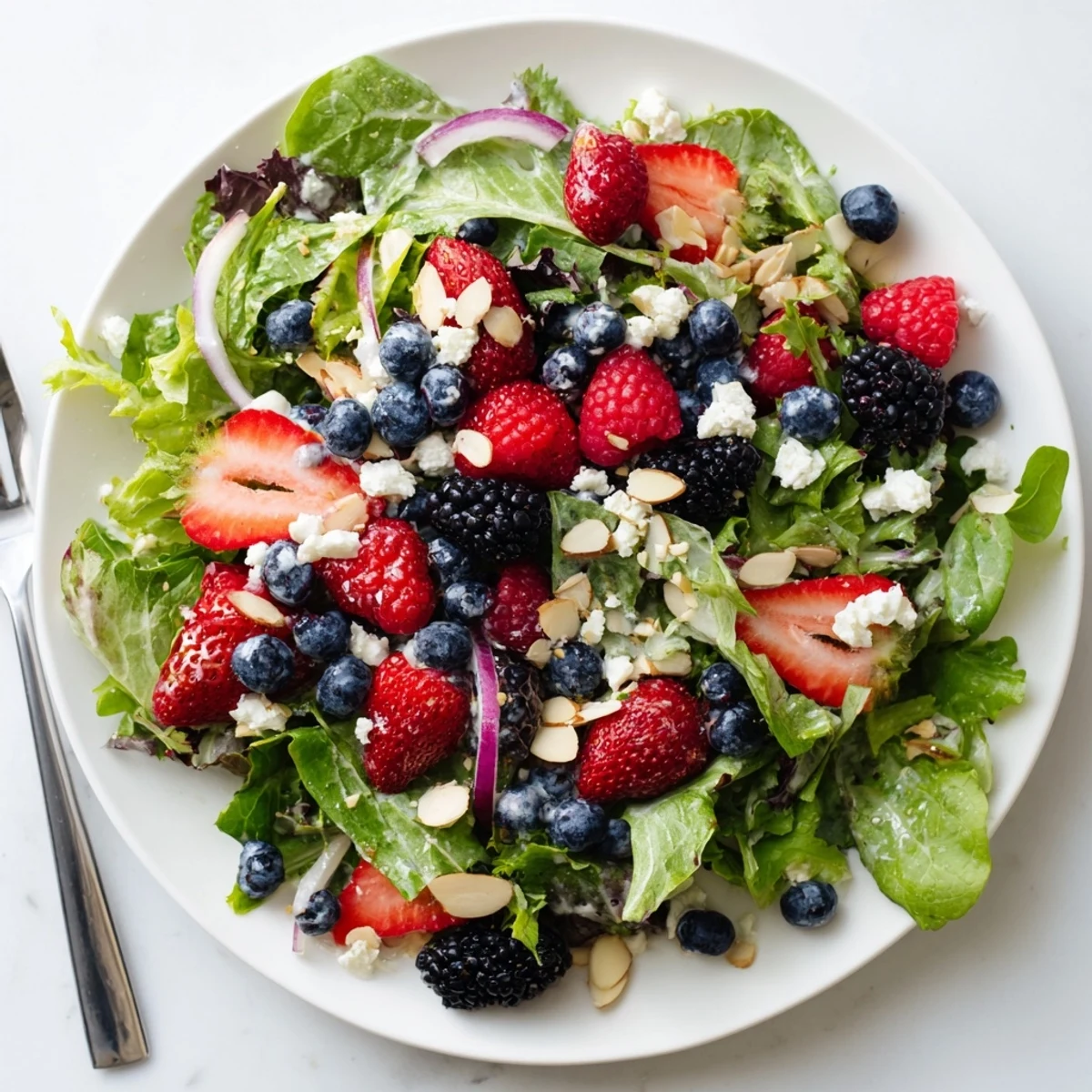 Fresh mixed greens, sliced strawberries, and blueberries tossed in creamy poppy seed dressing in a Berry Salad with Poppy Seed Dressing.