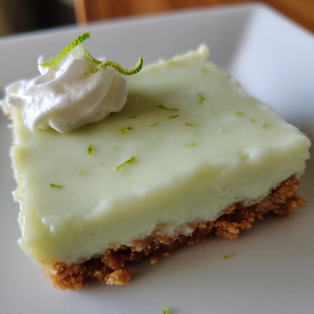 Freshly baked Key Lime Pie Bars with a golden graham cracker crust, topped with creamy tangy lime filling and a dollop of whipped cream.