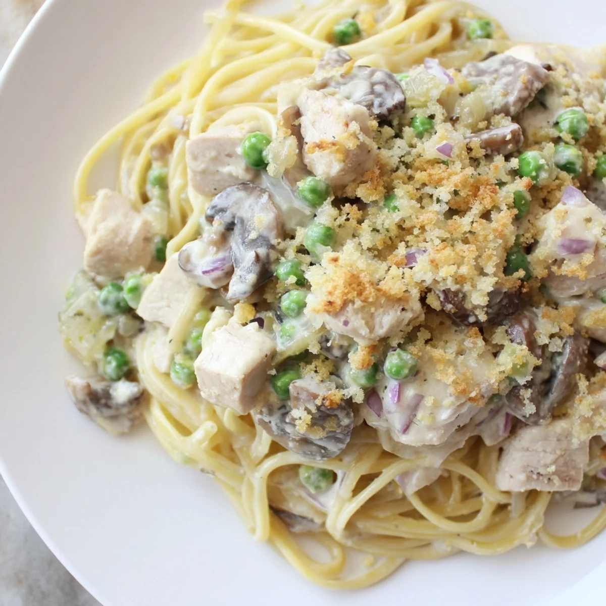 Golden, bubbly Turkey Tetrazzini with mushrooms and peas in a creamy sauce.