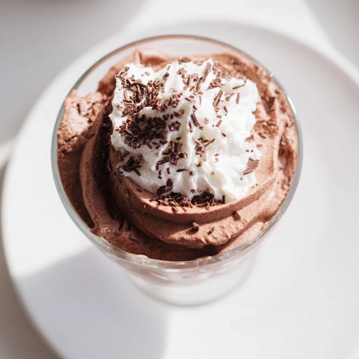 Silky Chocolate Mousse with Whipped Cream served in a chilled glass, topped with fluffy cream and rich chocolate shavings.
