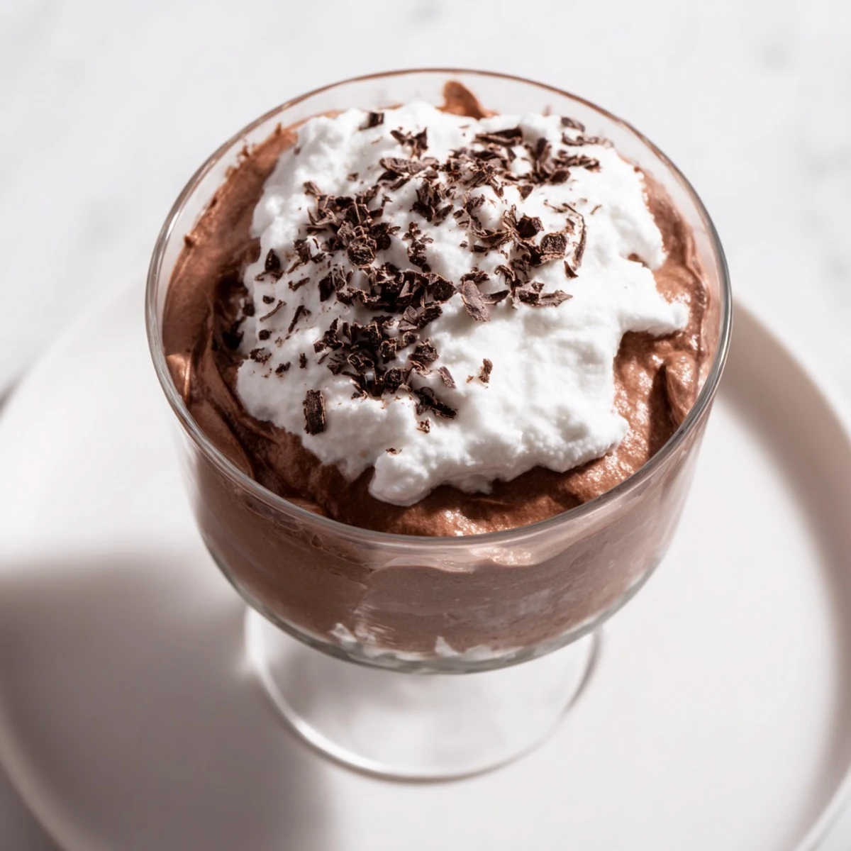 Luscious Chocolate Mousse with Whipped Cream layered in a dessert dish, crowned with billowy cream for a French-inspired finish.