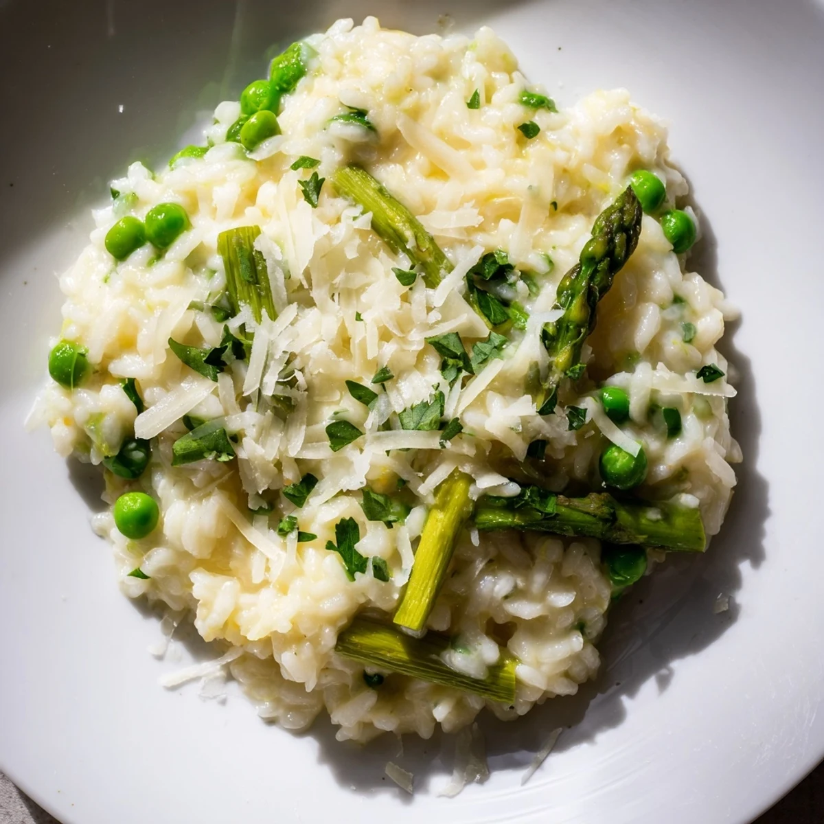 Spring Pea and Asparagus Risotto served warm in a white bowl garnished with fresh parsley and lemon zest.