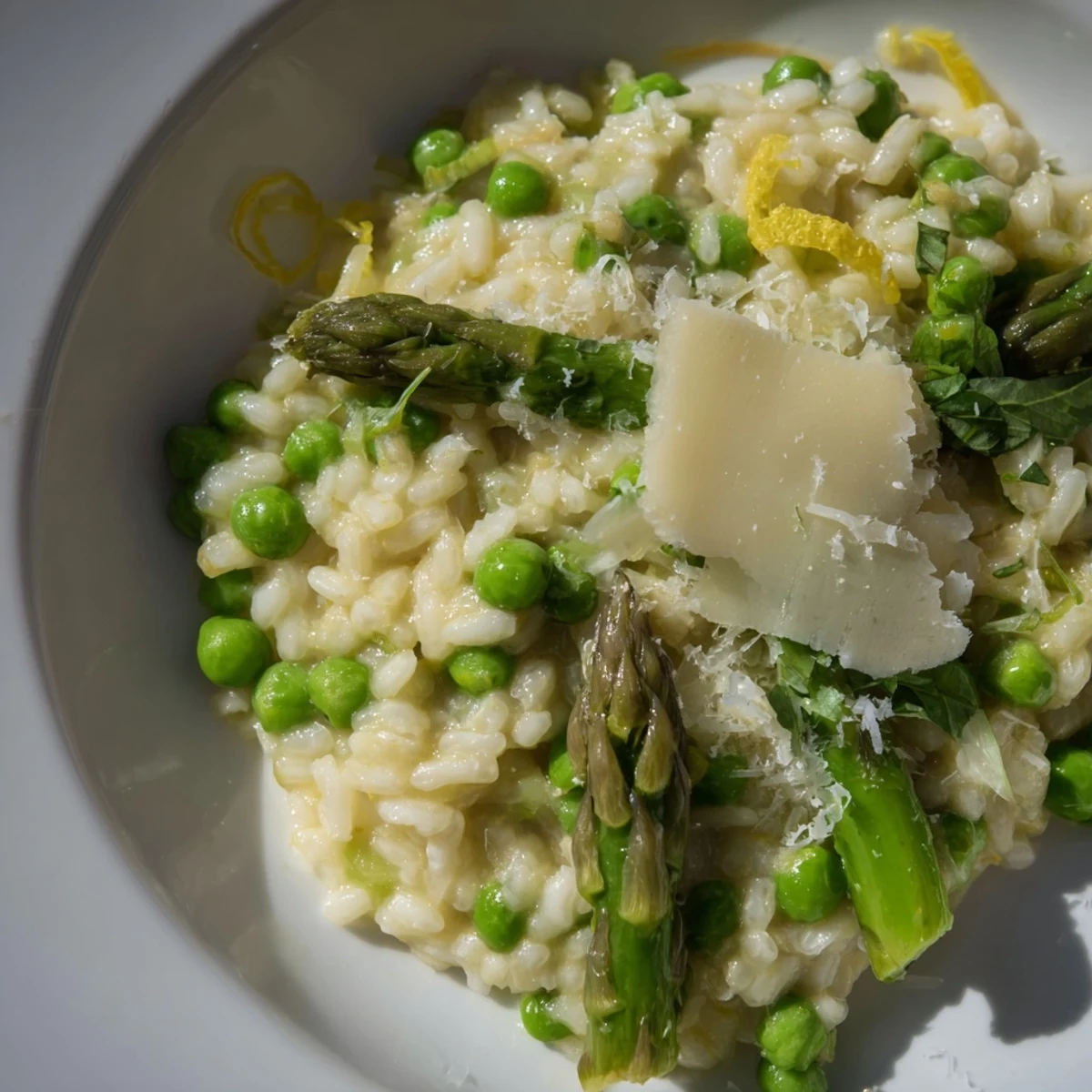Creamy Spring Pea and Asparagus Risotto in a white bowl, garnished with fresh parsley and lemon zest.