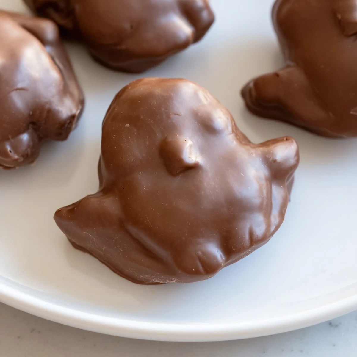 Fluffy marshmallow Peeps dipped in glossy chocolate and sprinkled with colorful sugar on a chilled baking sheet.