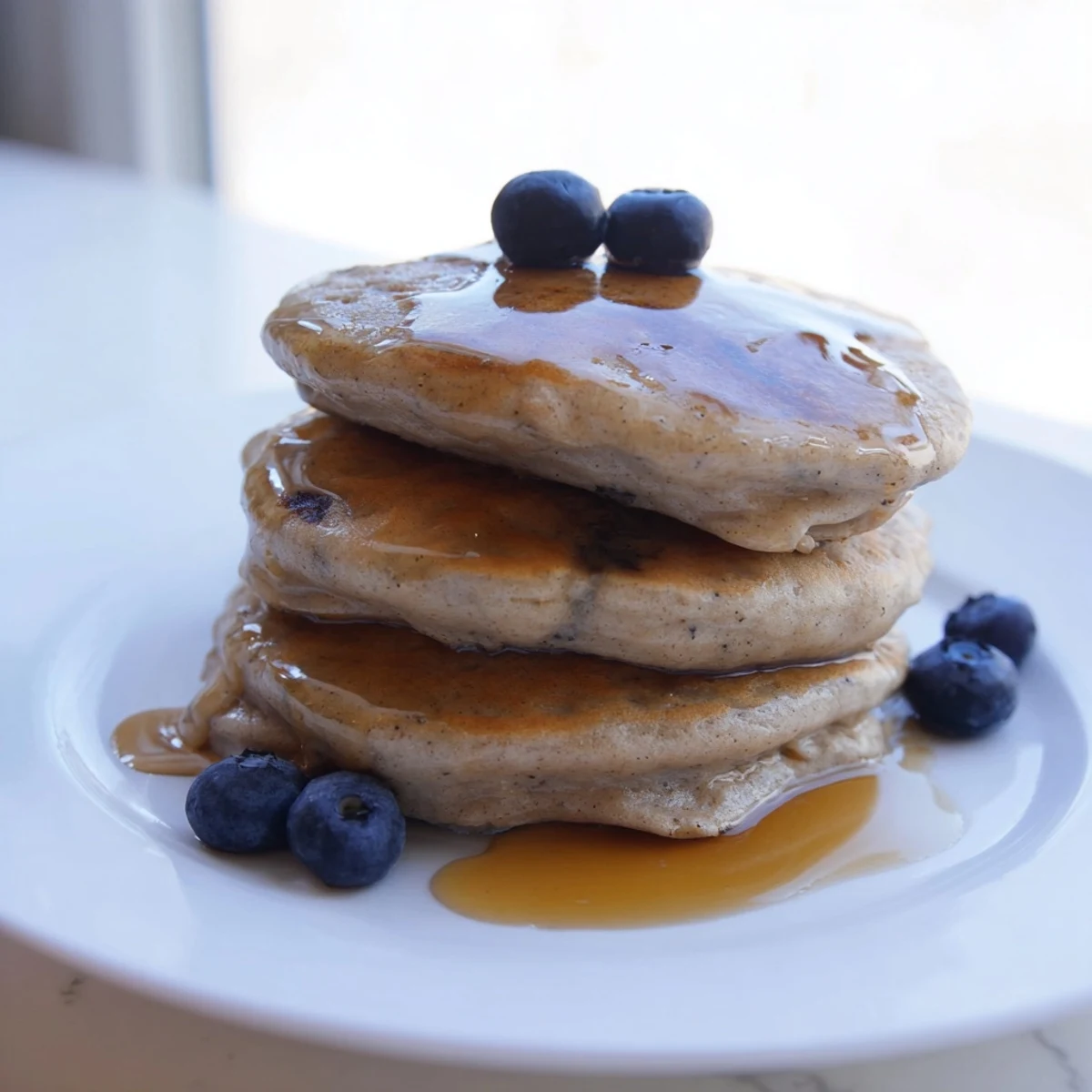Freshly cooked Sourdough Discard Pancakes stacked high on a plate, golden brown and fluffy, ready to be drizzled with maple syrup.