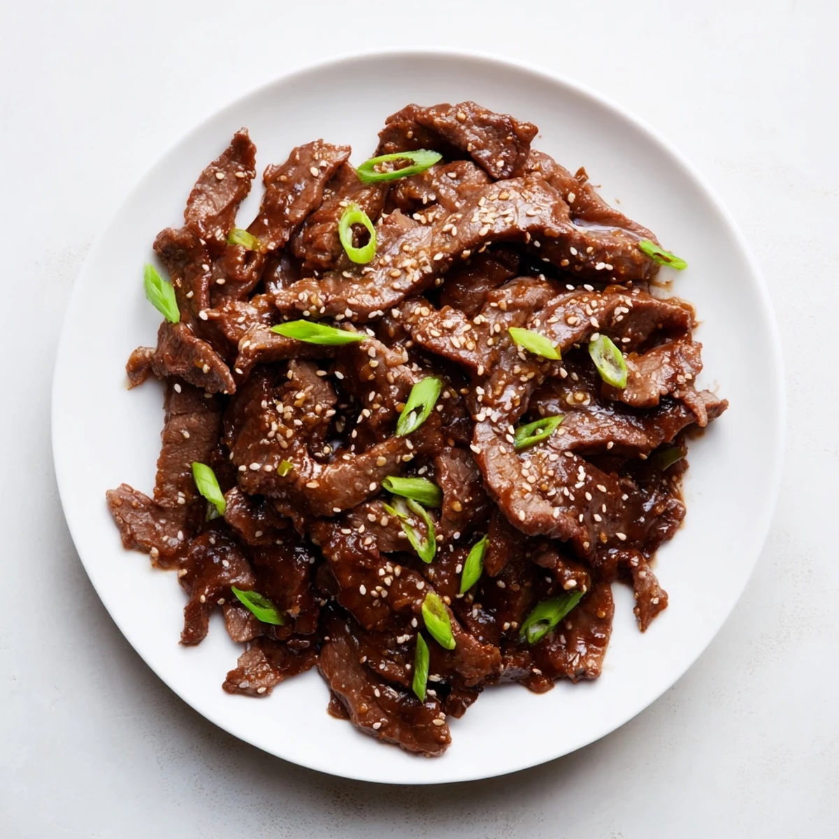 Steaming Ultimate Slow Cooker Mongolian Beef glistens with thick, savory-sweet sauce and toasted sesame seeds.