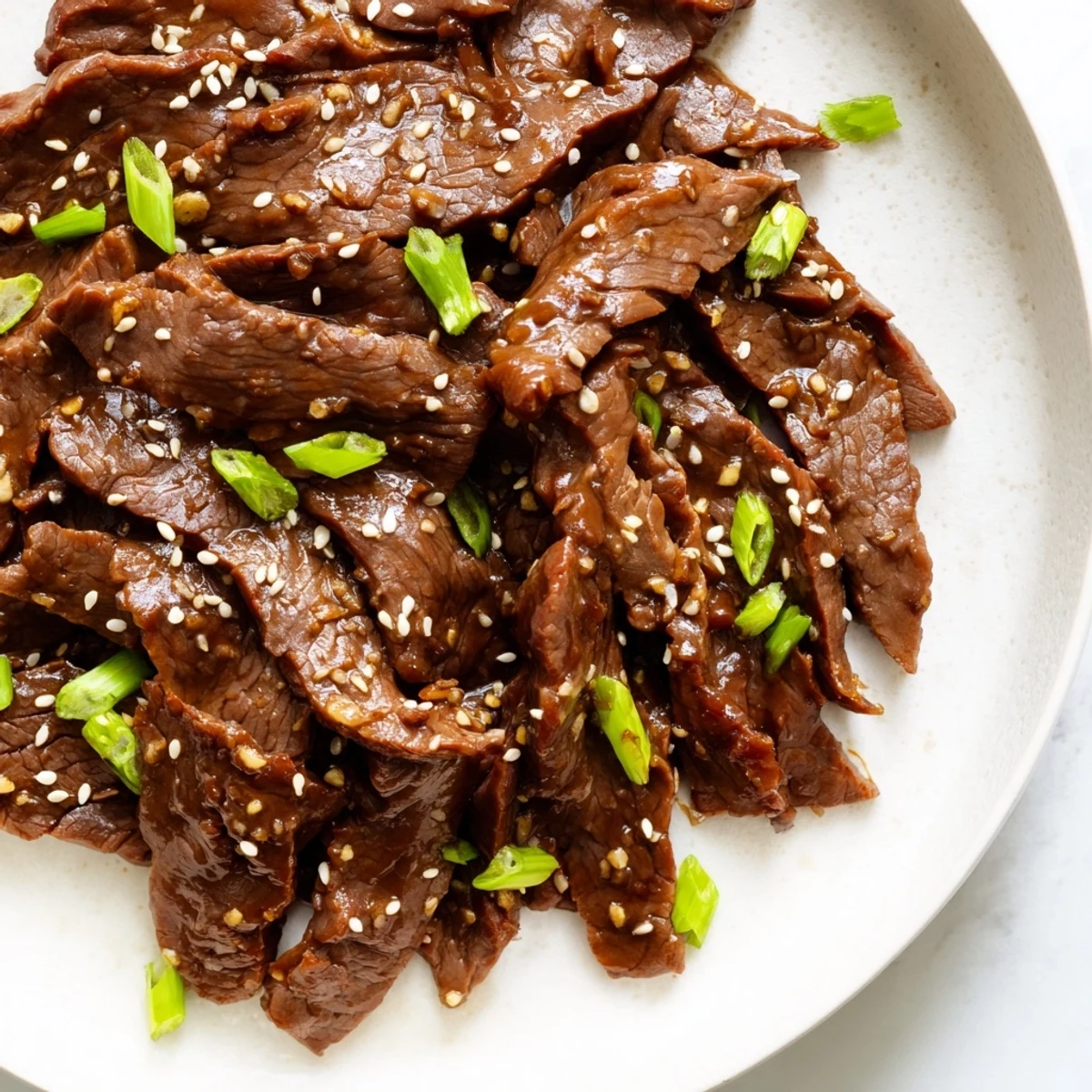 Served over jasmine rice, Ultimate Slow Cooker Mongolian Beef is garnished with fresh green onions.