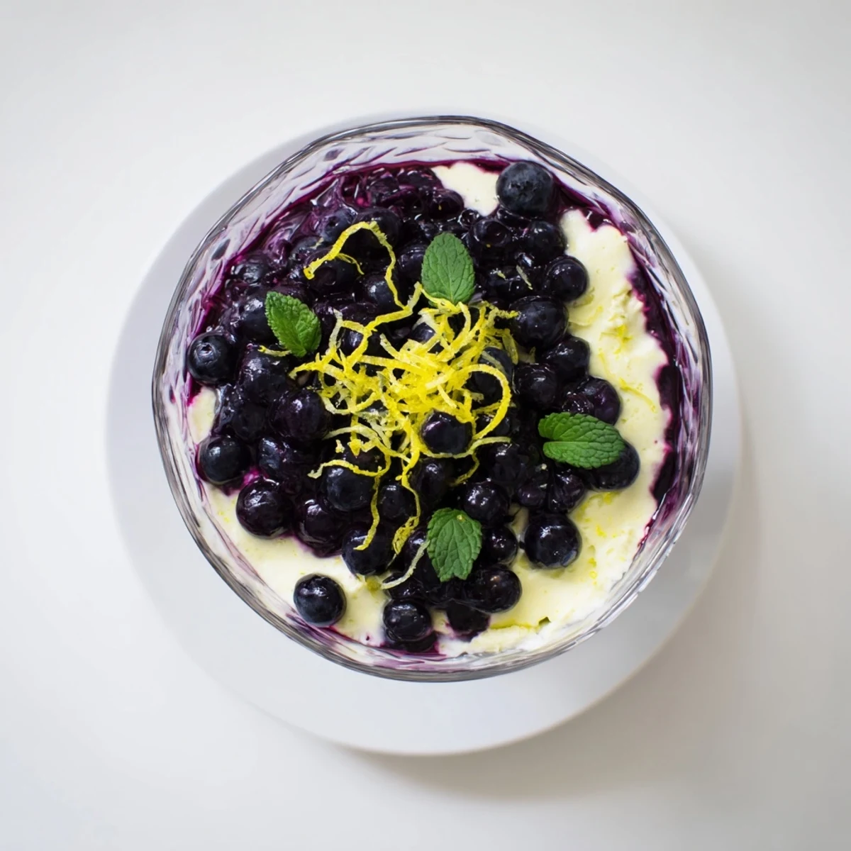Garnished with fresh blueberries and mint, this Lemon Blueberry Mousse layers smooth citrus cream and vibrant compote in a clear glass.