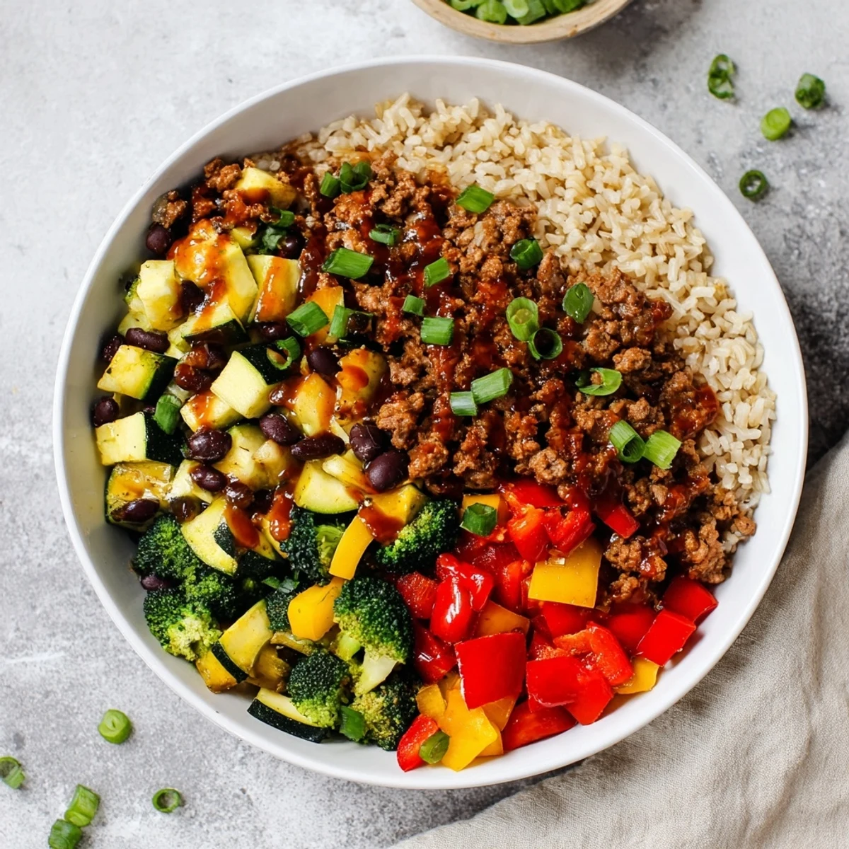 Close-up of meal prep containers showing Viral Hot Honey Ground Beef Bowl, avocado, and a glossy spicy glaze.