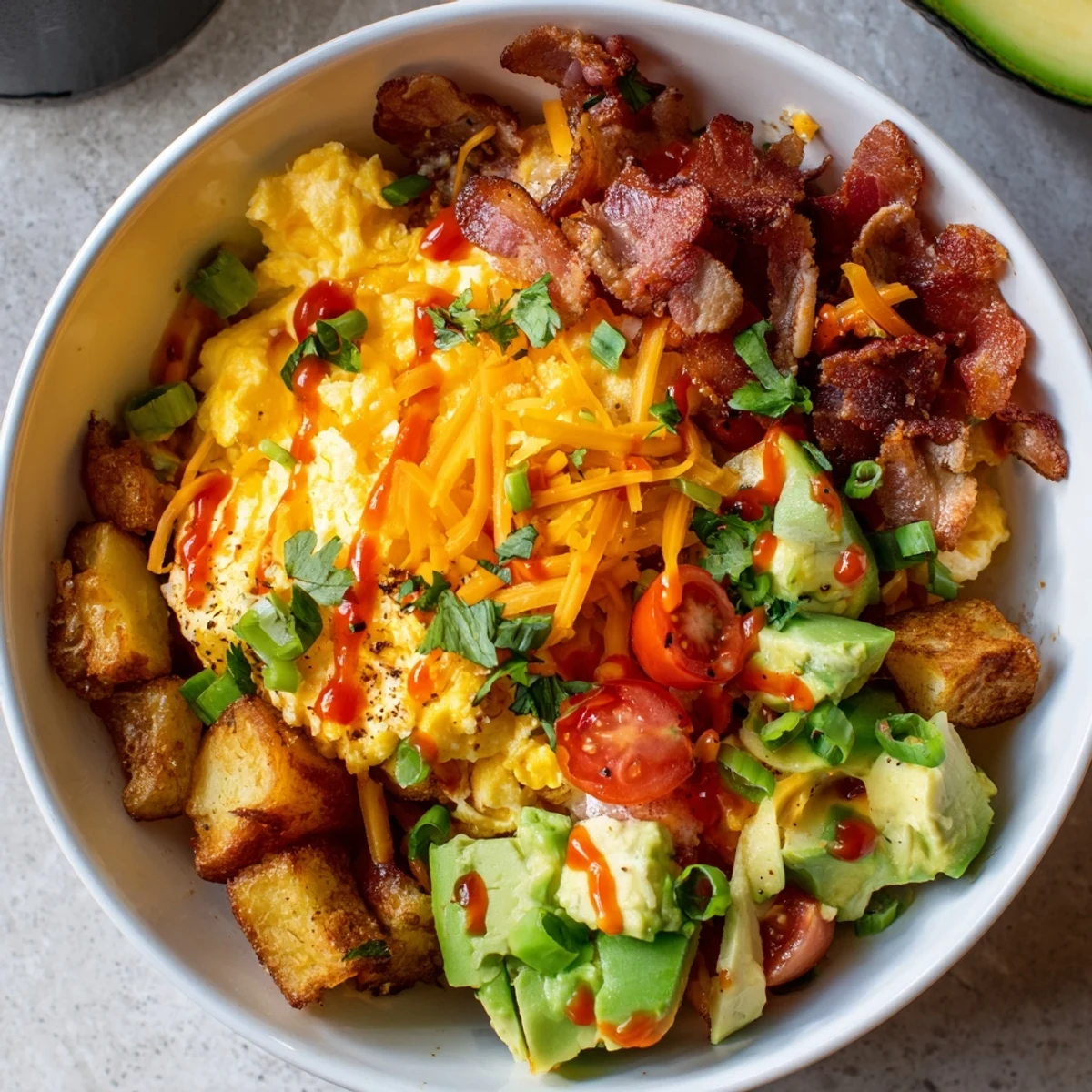 A hearty Loaded Breakfast Bowl with golden potatoes, crispy bacon, and fresh tomatoes, served hot for a satisfying morning meal.