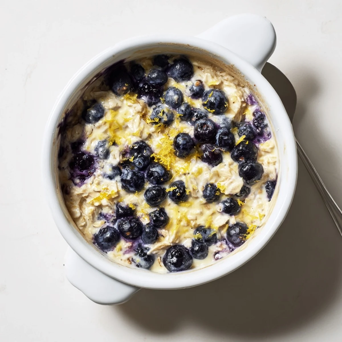 A close-up of warm, protein-rich Baked Blueberry Cottage Cheese Breakfast Bowls served with a honey drizzle.