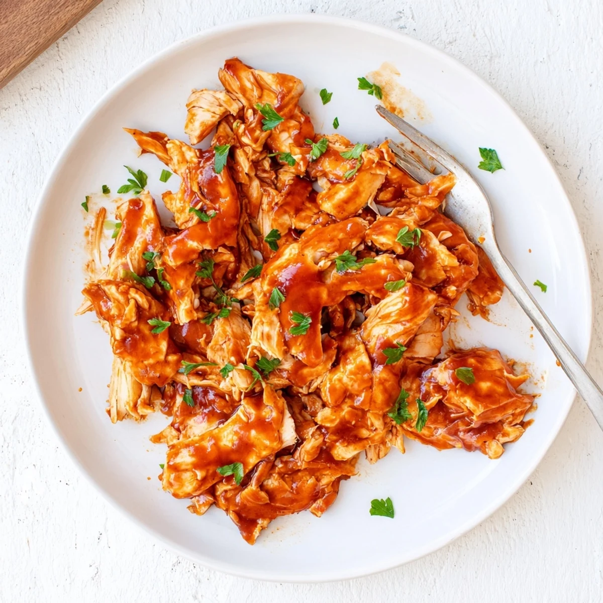 Tender shredded Sweet Baby Rays Crockpot Chicken piled high on a soft bun with fresh parsley. This saucy, savory dish is a classic American main course for any weeknight.