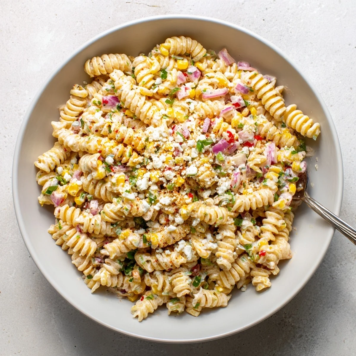 A vibrant Mexican Street Corn Pasta Salad featuring charred corn, rotini, jalapeños, and red onion tossed in a tangy sauce.