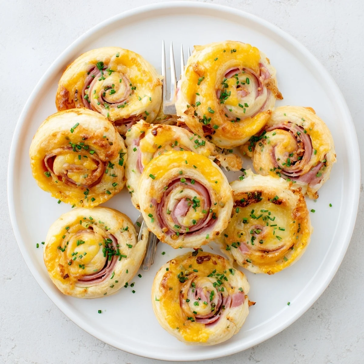 Sliced Easter Ham Cheddar Pinwheels arranged on a platter, revealing swirls of herbs and sharp cheddar for spring gatherings.