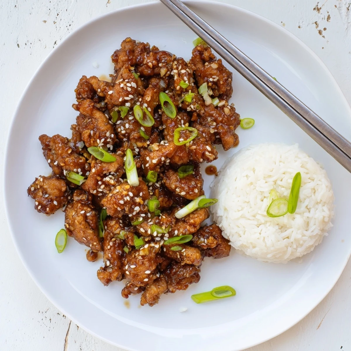 Mongolian chicken served over steamed white rice and garnished with green onions and sesame seeds