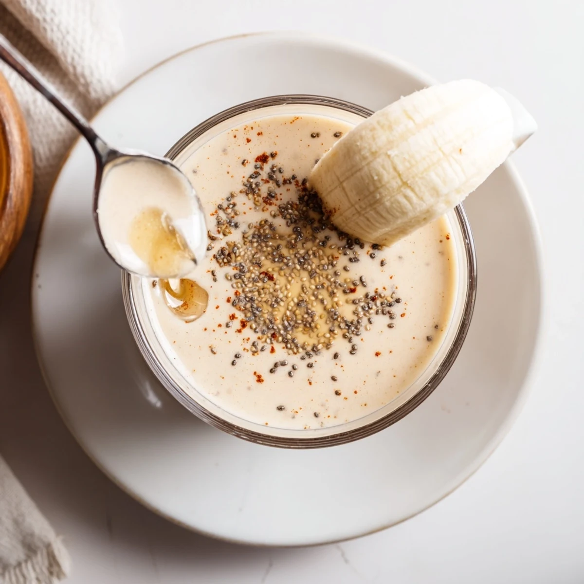 Protein-packed Greek yogurt banana smoothie in a tall glass topped with granola and cinnamon dust