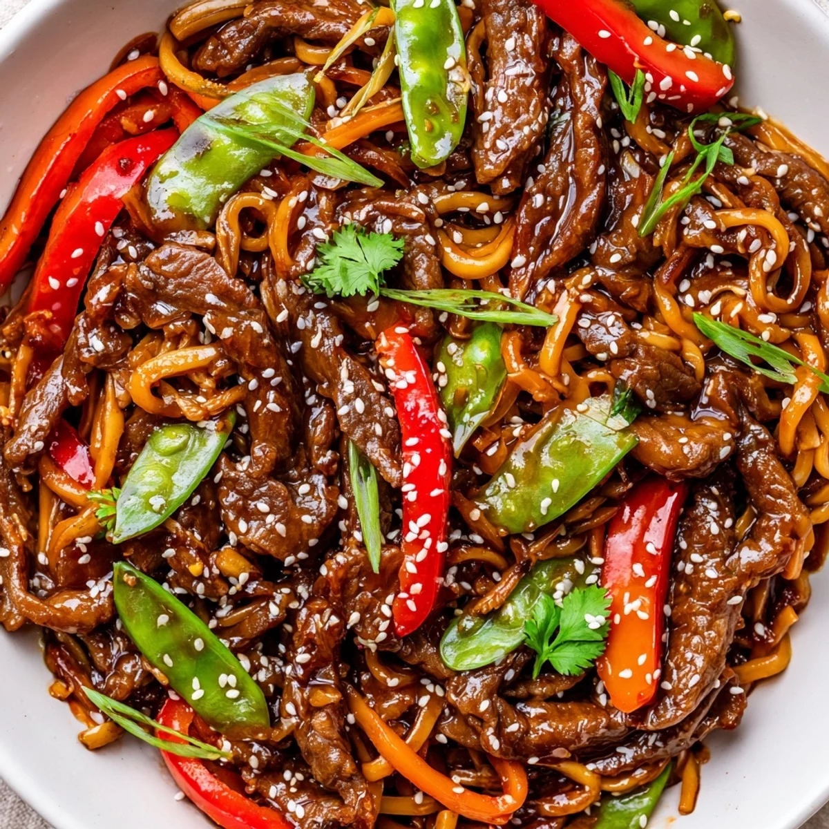 Tender sliced beef stir-fried with chewy noodles and colorful veggies coated in thick glaze