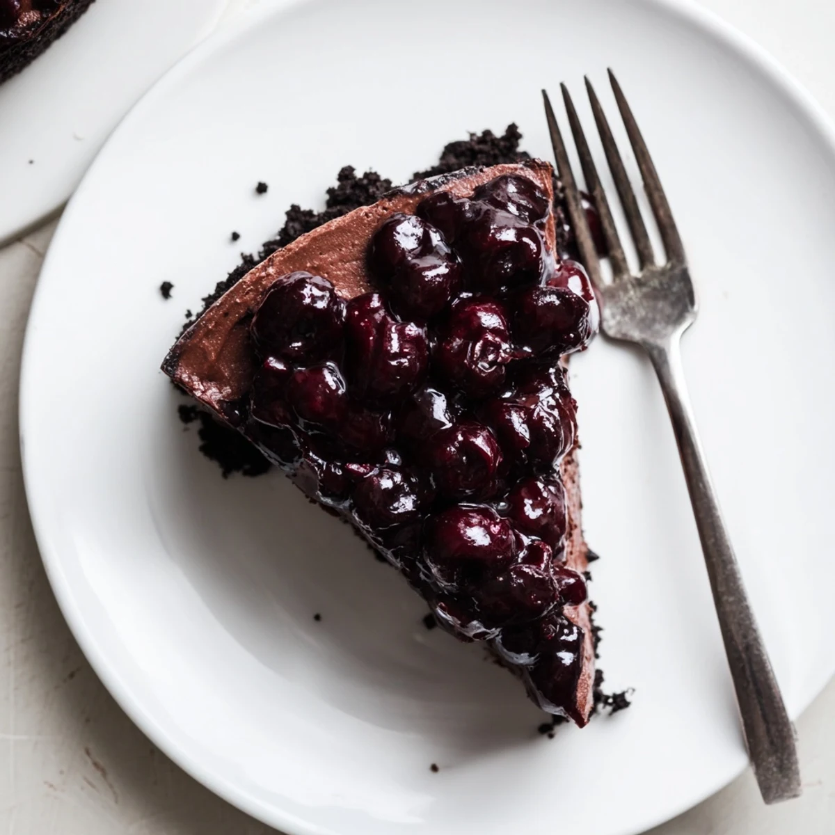 Homemade dark chocolate cherry cheesecake featuring ruby cherry compote drizzled over rich chocolate layer