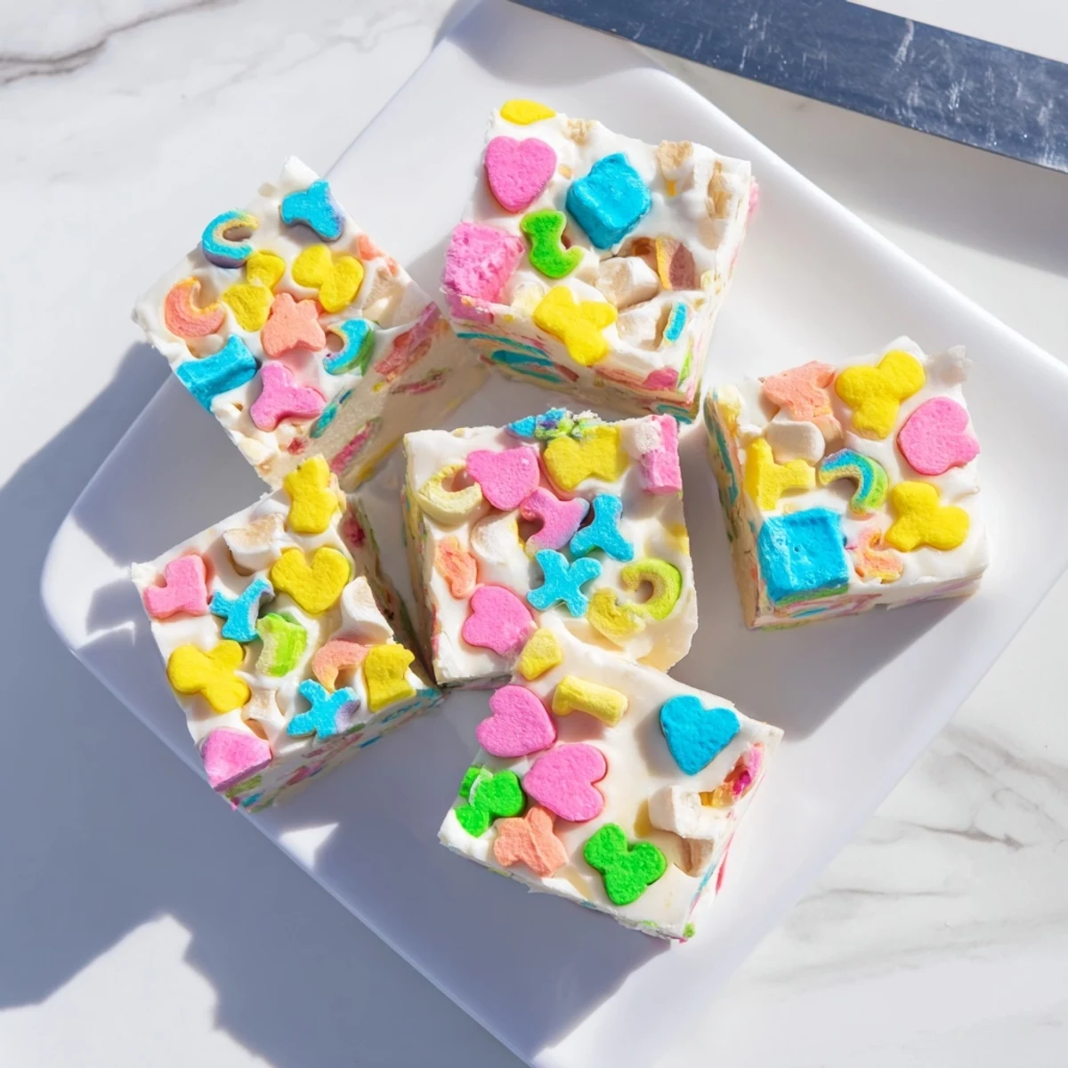 Thick cut pieces of Easy Lucky Charms Fudge showing swirled white chocolate and scattered rainbow marshmallows