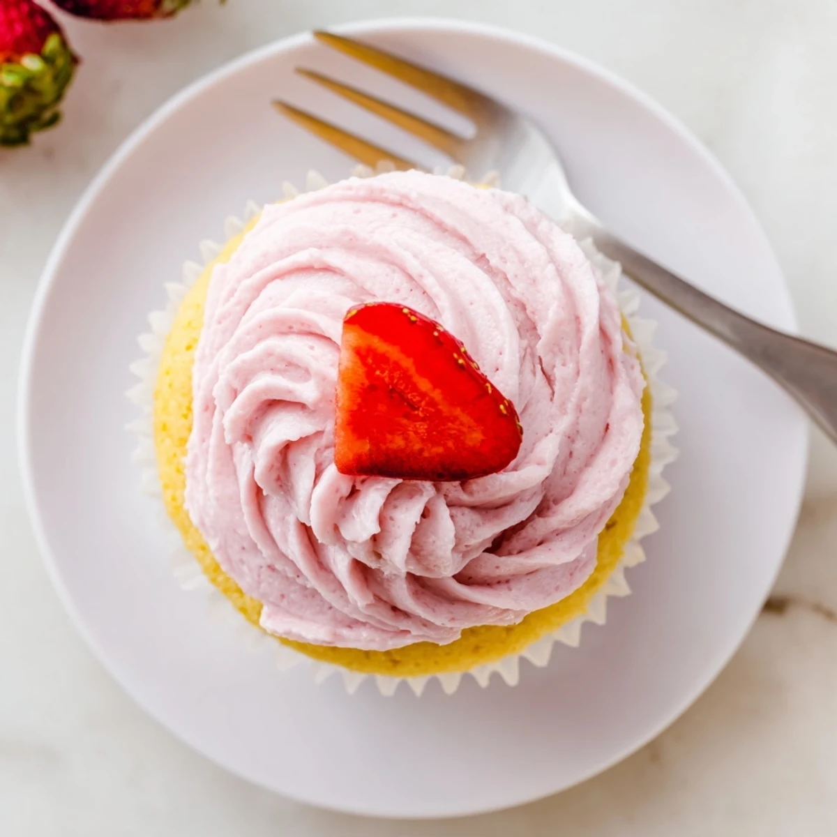 Close up of zesty lemon cupcakes with naturally pink strawberry frosting piped in decorative swirls