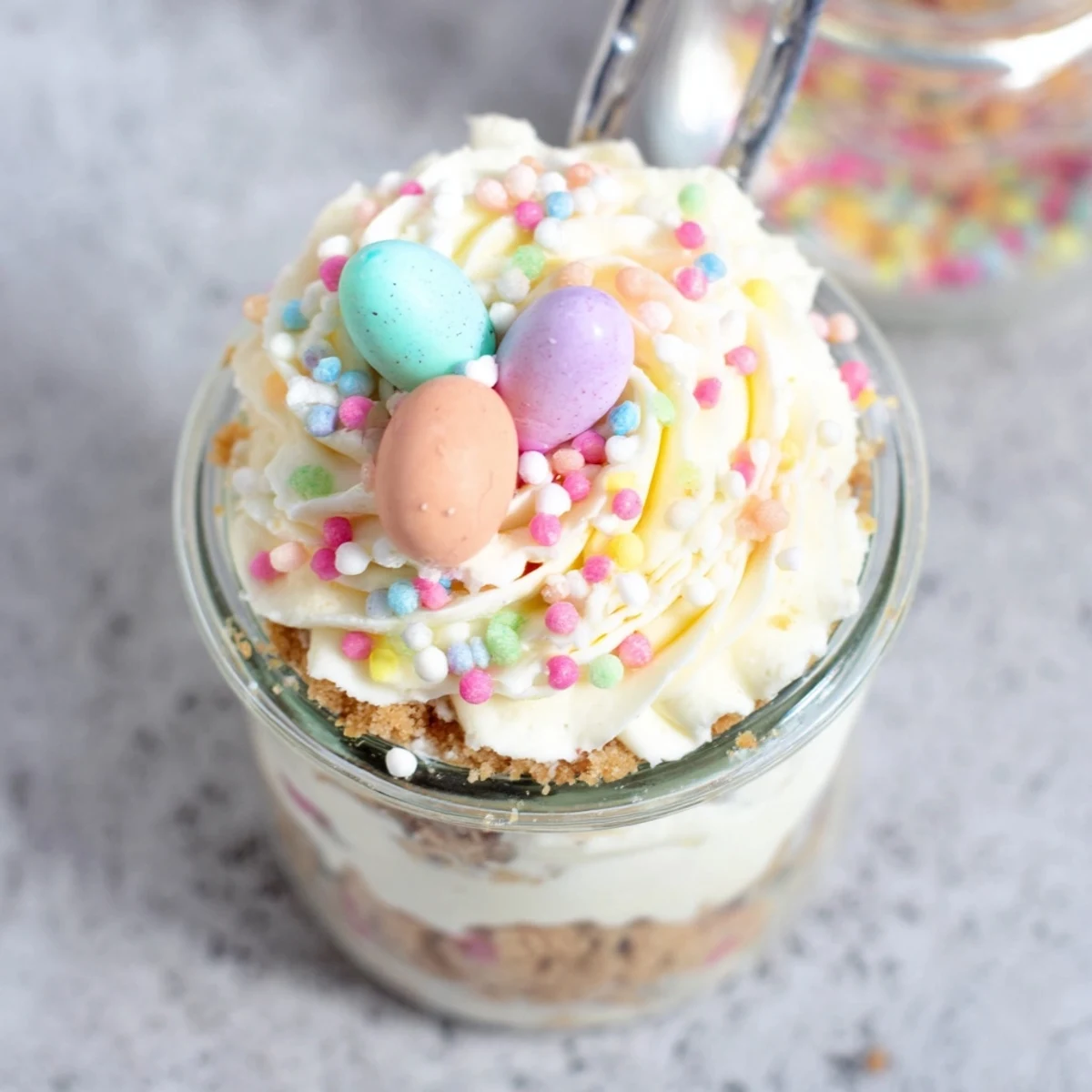 Creamy Easter Egg Cheesecake Jars layered with crushed cookies and colorful mini chocolate eggs nestled inside
