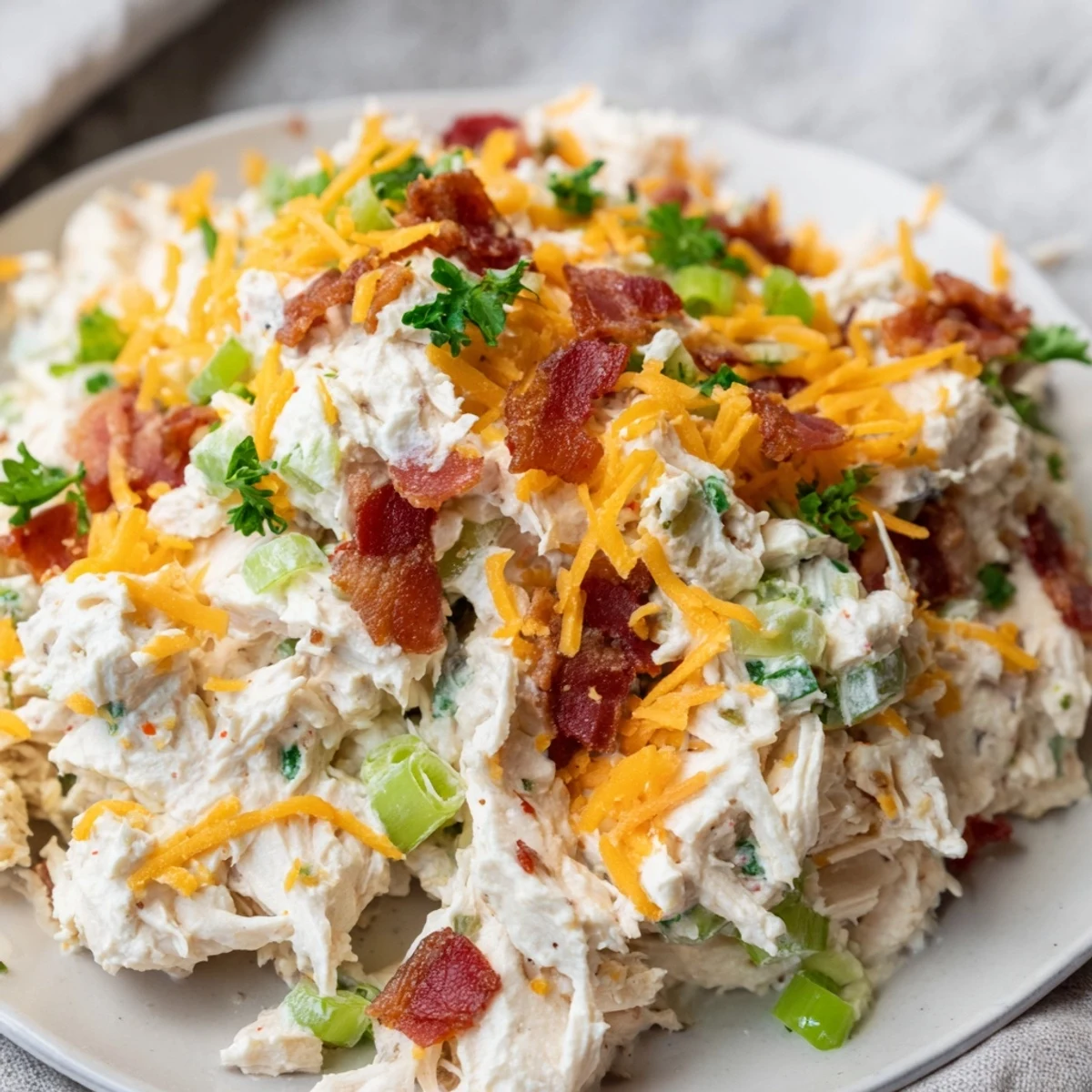 Bowl of spicy jalapeno popper cottage cheese chicken salad topped with crumbled bacon and fresh parsley