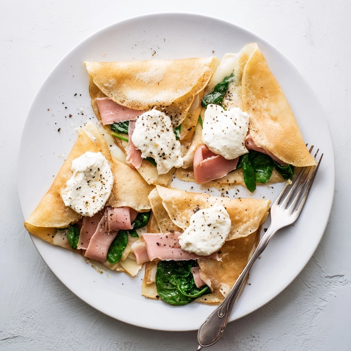 Golden savory crepes filled with melted Gruyère cheese, ham, and fresh spinach