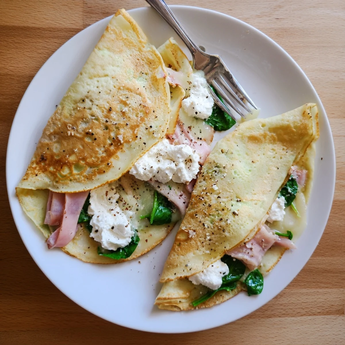 Delicate French savory crepes rolled with creamy spinach and grated cheese topping