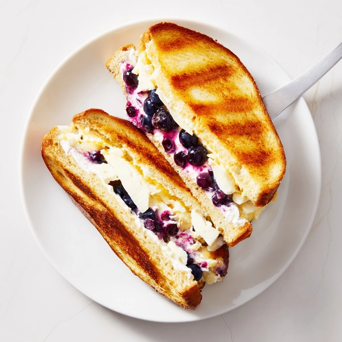 Golden blueberry grilled cheese sandwich with melted cheddar oozing between buttery toasted sourdough bread slices