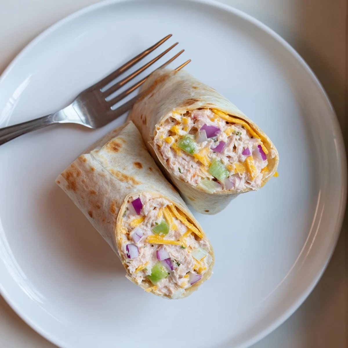 Golden grilled tuna melt wrap with melted cheddar cheese oozing from warm tortilla