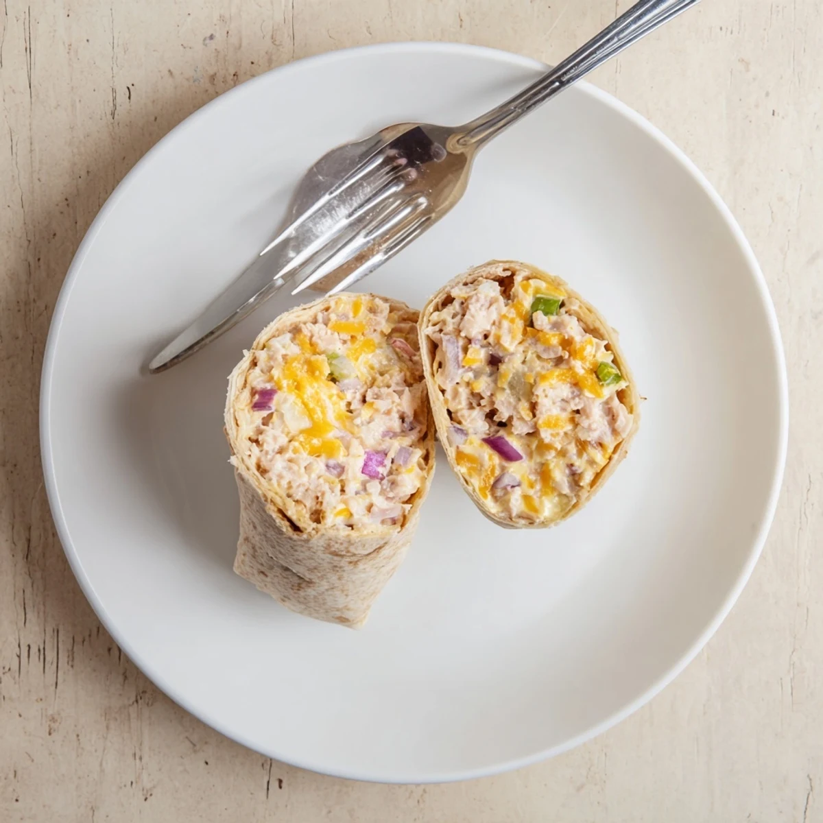 Tuna melt wrap sliced in half revealing creamy tuna salad and red onion filling