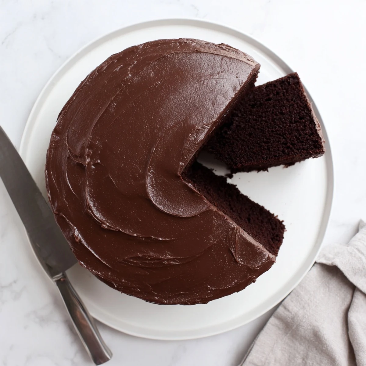 Decadent chocolate cake layered with silky frosting on a white serving plate