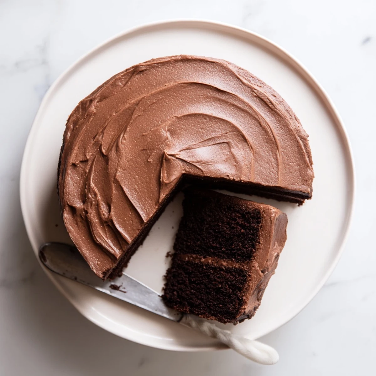 Moist chocolate cake slice revealing tender crumb topped with rich buttercream frosting