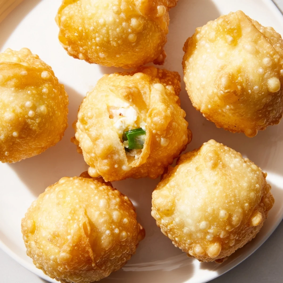 Platter of fried Crab Rangoon Bombs served with sweet chili dipping sauce and fresh green onion garnish