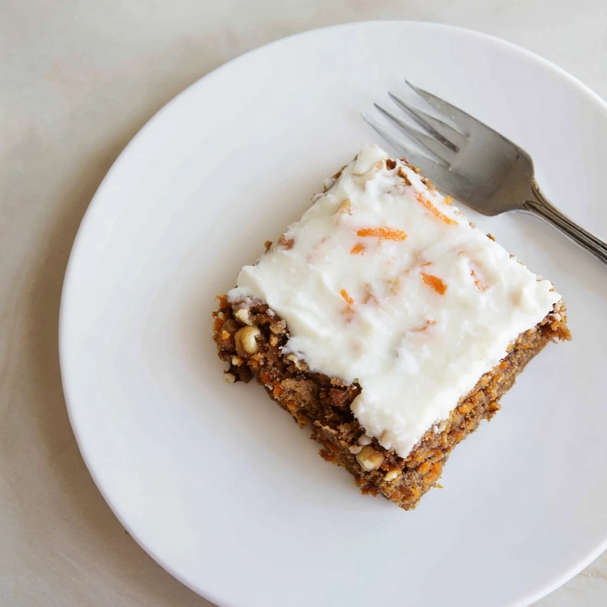 Moist spiced carrot cake bars sliced into squares showing thick cream cheese frosting layer