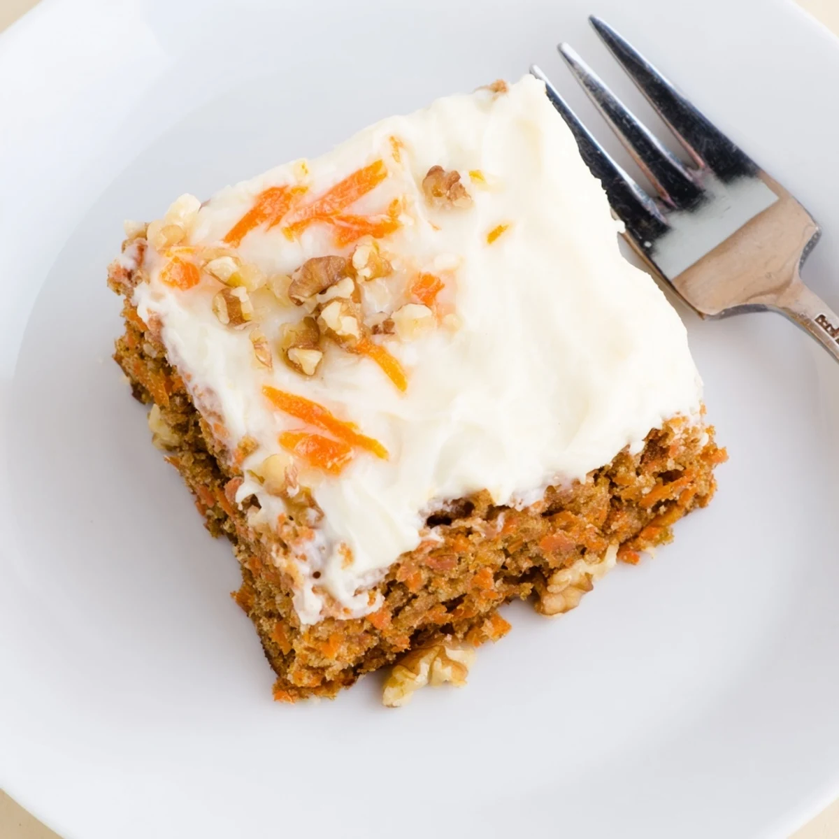 Golden carrot cake bars with creamy white frosting close-up view with visible shredded carrot texture