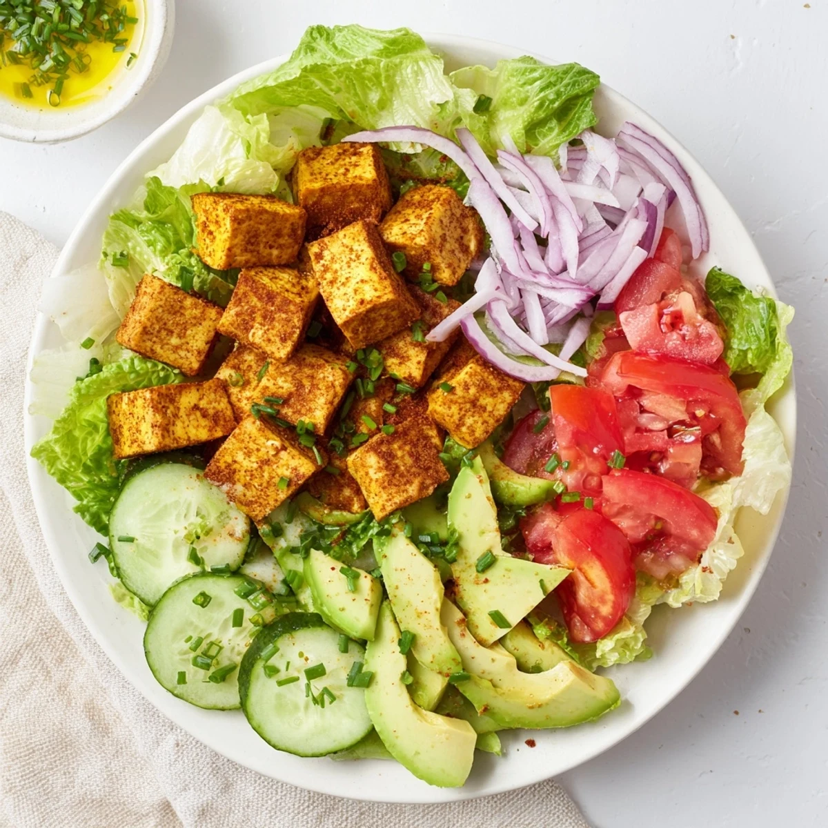 Golden smoky tofu cubes atop crisp lettuce and juicy ripe tomatoes in a summer salad