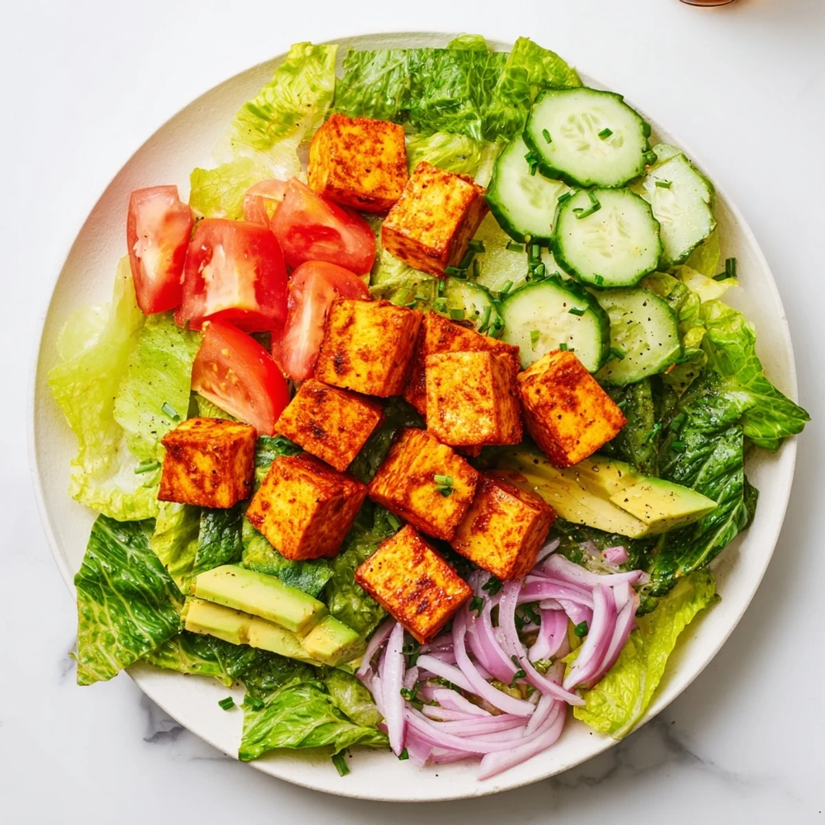 Close-up of warm spiced tofu served over crisp lettuce tomato salad for refreshing summer meals