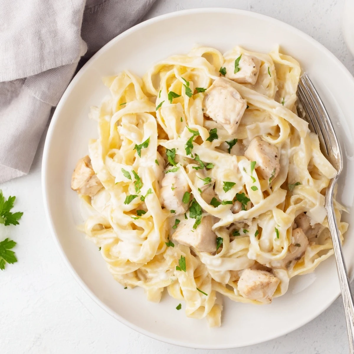 A comforting bowl of Instant Pot chicken alfredo topped with fresh parsley and extra grated parmesan cheese