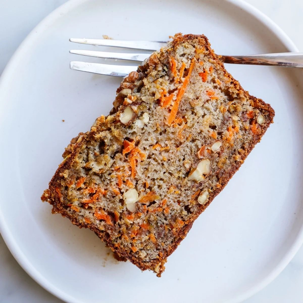 Freshly baked carrot cake banana bread cooling on a wire rack with golden crust and steam rising from the warm spiced loaf